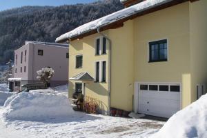 a yellow house with a garage in the snow at Appartment Shelley in Vandans