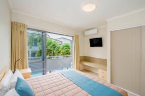 a bedroom with a bed and a large window at Raumati Sands Resort in Paraparaumu Beach