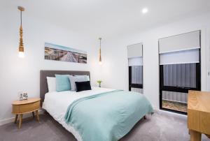 a bedroom with a large bed and two windows at Lamour Holiday Beach House in Gold Coast