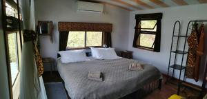 a bedroom with a bed with white sheets and two windows at Mama Out of Africa in Livingstone