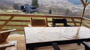 a table and chairs on a porch with a view of a house at Pensiunea Maria-Bucovina in Vatra Moldoviţei