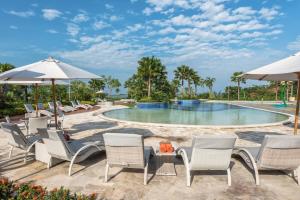 a pool at a resort with chairs and umbrellas at HARRIS Resort Barelang Batam in Sekupang