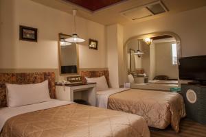 ein Hotelzimmer mit zwei Betten und einem Spiegel in der Unterkunft 真正好旅店 Good Hotel in Fengyuan