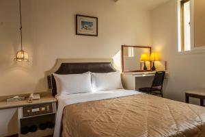 ein Schlafzimmer mit einem Bett, einem Schreibtisch und einem Spiegel in der Unterkunft 真正好旅店 Good Hotel in Fengyuan