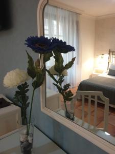 a mirror with a vase with flowers in a room at Las Nieves in Granada