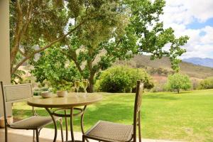 - une table et des chaises sur une terrasse avec vue sur un champ dans l'établissement Piekenierskloof Mountain Resort by Dream Resorts, à Citrusdal