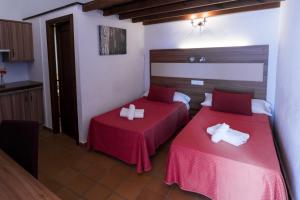 two beds in a room with red sheets at Hostal Rural La Fonda Del Rocio in El Rocío