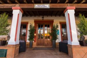 Hostal Rural La Fonda Del Rocio في إل روثيو: باب امامي لمبنى به نباتات الفخار