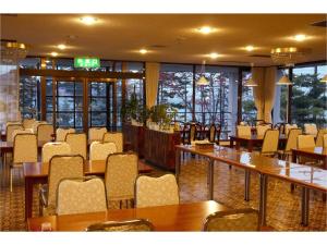 a dining room with tables and chairs and windows at Hotel Nakanoshima in Sobetsu