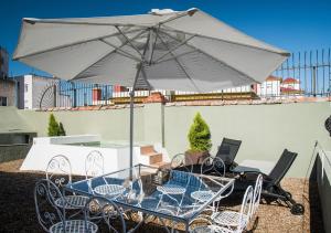 a table and chairs under an umbrella on a patio at Slow Suites Maestranza in Seville