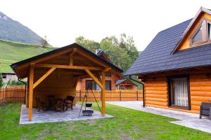 a wooden cabin with a table and chairs in front of it at Chata Zazrivka in Biela