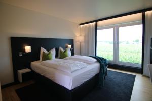 um quarto com uma cama grande e uma janela grande em NU Hotel by WMM Hotels em Neu-Ulm