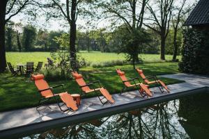 a group of chairs sitting next to a body of water at The Annex Retreat - a luxury countryside villa in Geijsteren