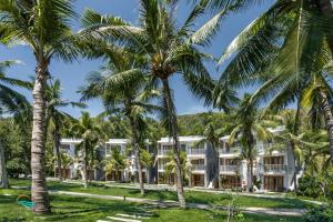 a hotel with palm trees in front of it at Casa Marina Resort in Quy Nhon