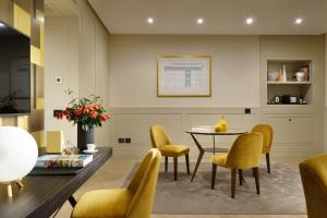 a dining room with a table and yellow chairs at Margutta 19 - Small Luxury Hotels of the World in Rome