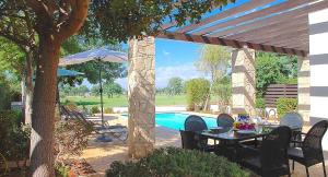 un patio con tavolo e sedie accanto alla piscina di 3 bedroom Villa Cardia with private pool, Aphrodite Hills Resort a Kouklia