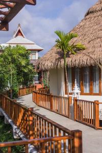 a wooden walkway leading to a house with a thatch roof at Phusanfah Resort in Mae Taeng
