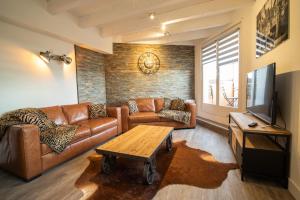 a living room with a leather couch and a television at Le rohan sawadee in Colmar