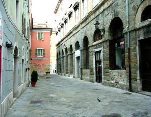an empty alley in a city with buildings at Piazza Grande City Residence in Trieste