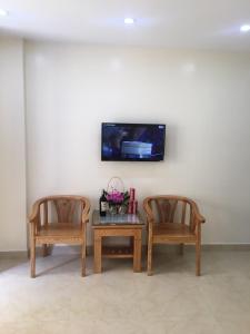 2 sedie e un tavolo con tv a muro di Minh Đức hotel a Cat Ba