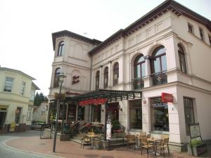 ein Gebäude mit Tischen und Stühlen auf einer Straße in der Unterkunft Haus Lucie in Heringsdorf