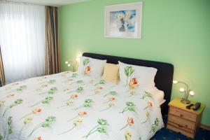 a bed with a white comforter with flowers on it at Hotel Gästehaus Priester in Limburg an der Lahn