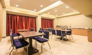 una sala de conferencias con mesas, sillas y cortinas rojas en The Legend Hotel- Santacruz Near Mumbai International Airport en Bombay
