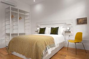 een witte slaapkamer met een bed en een gele stoel bij Host Wise - Oporto Classic Apartment in Porto
