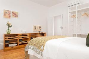 een witte slaapkamer met een bed en een houten dressoir bij Host Wise - Oporto Classic Apartment in Porto +29 foto's