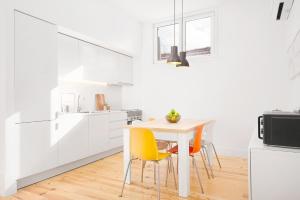 a white kitchen with a table and yellow chairs at Oporto Classic Apartment in Porto