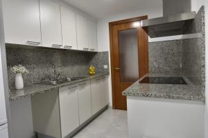 a kitchen with white cabinets and a sink at Apartament Gredera in Olot