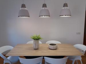 a dining room table with white chairs and lights at Apartament Gredera in Olot