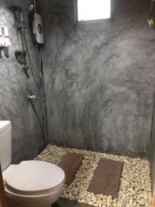 baño con aseo y suelo de piedra en Mook Tamarind Resort en Ko Mook