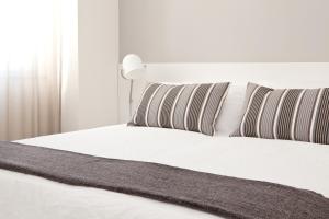 a white bed with striped pillows and a white headboard at Palazzo Talenti 1907 in Trieste