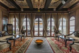 a living room filled with furniture and a large window at Brijrama Palace, Varanasi - Heritage boutique hotel by the Ganges in Varanasi