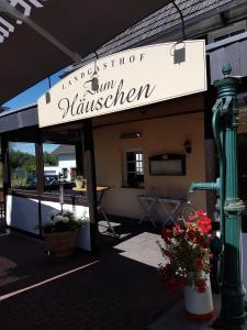 um sinal para um restaurante com flores em frente em Landgasthof Zum Häuschen em Rösrath