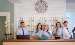 a group of people standing behind a counter with their arms crossed at Hotel Punta Nord Est in Castellammare del Golfo