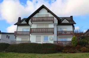 Casa blanca con balcones de madera. en Ferienwohnung Little Home in Winterberg-Neuastenberg, en Winterberg