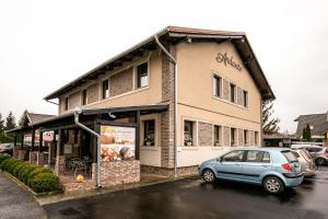 un coche azul estacionado frente a un edificio en Andante Pension & Restaurant, en Szentgotthárd