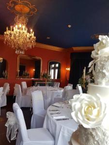 a room with white tables and white chairs and a chandelier at The Cleveland Tontine in Northallerton