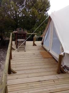 una terraza de madera con una tienda y una silla en Monte da Tojeirinha, en Montargil