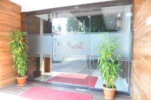 eine Tür zu einem Hotel mit zwei Topfpflanzen in der Unterkunft Emporium Hotel in Mangaluru