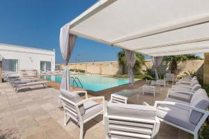 eine Terrasse mit weißen Stühlen und einem Pool in der Unterkunft Villa Albarosa by Perle di Puglia in Ruffano