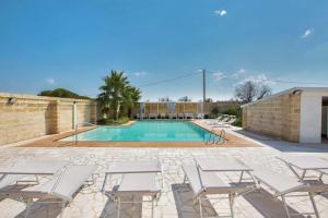 Una piscina con sillas blancas y una piscina. en Villa Albarosa by Perle di Puglia, en Ruffano