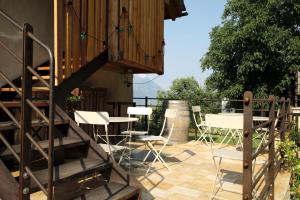 un patio con mesas y sillas y una escalera de madera en La casa di paglia B&B, en Verrayes