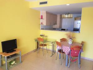 a kitchen with a table and chairs and a television at Magnífico apartamento junto al canal principal. in Empuriabrava