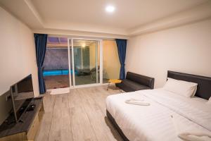 ein Hotelzimmer mit einem Bett und einem TV in der Unterkunft Villa Navin Premiere Pool Villa in Jomtien Beach
