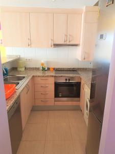 a kitchen with white cabinets and a stainless steel refrigerator at Magnífico apartamento junto al canal principal. in Empuriabrava +27 photos