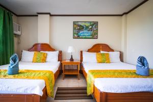 Blue Corals Beach Resort في جزيرة مالاباسكوا: غرفة فندقية بسريرين وطاولة