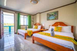 a hotel room with two beds and a balcony at Blue Corals Beach Resort in Malapascua Island